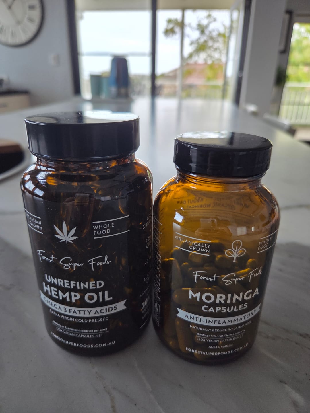 Bottles of Forest Super Foods unrefined hemp oil and moringa capsules, both whole food supplements known for moringa powder benefits, omega-3 fatty acids, and natural wellness.